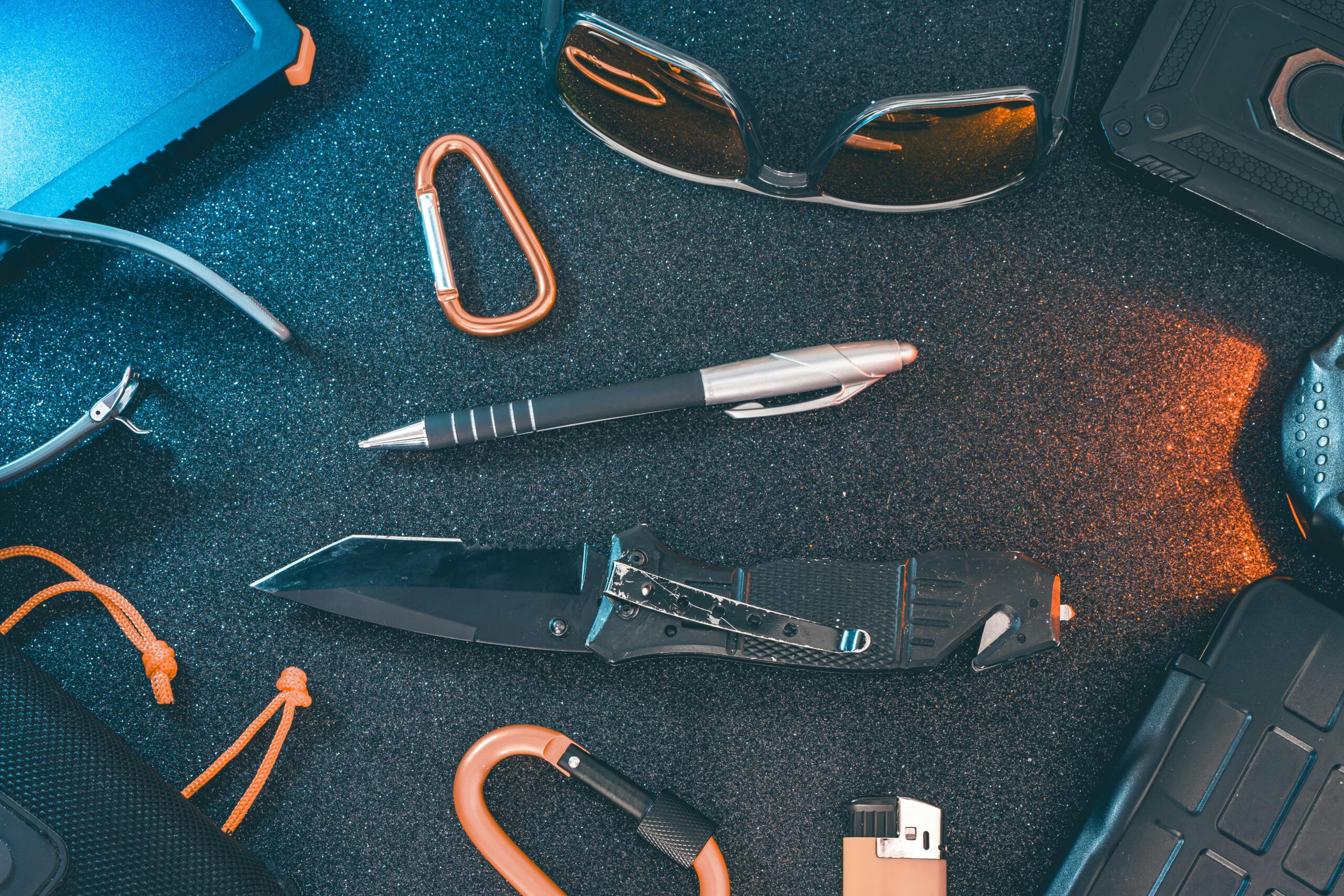 Everyday carry flat lay — pocket knife, watch, wallet, flashlight on a dark surface