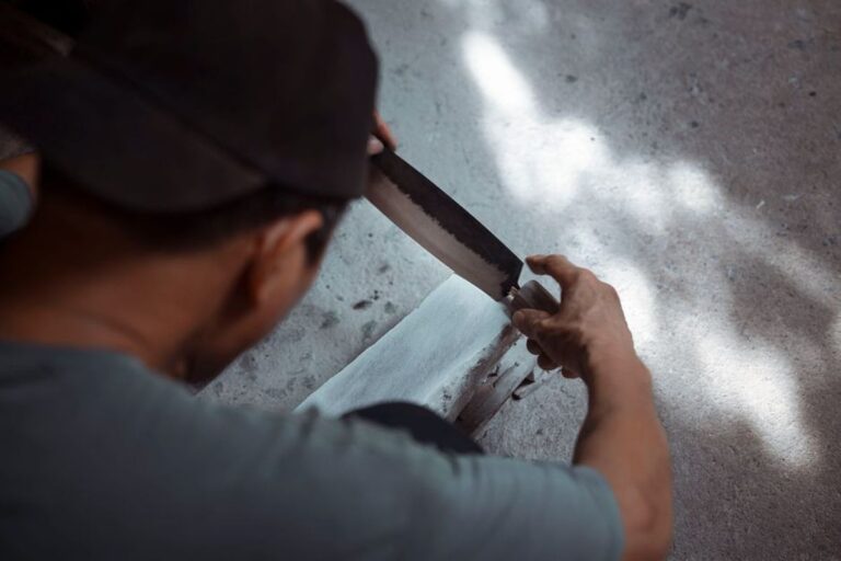 Sharpening a budget EDC knife blade on a whetstone by hand