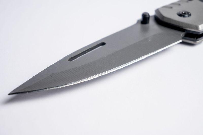Macro close-up of a pocket knife blade tip showing grind lines