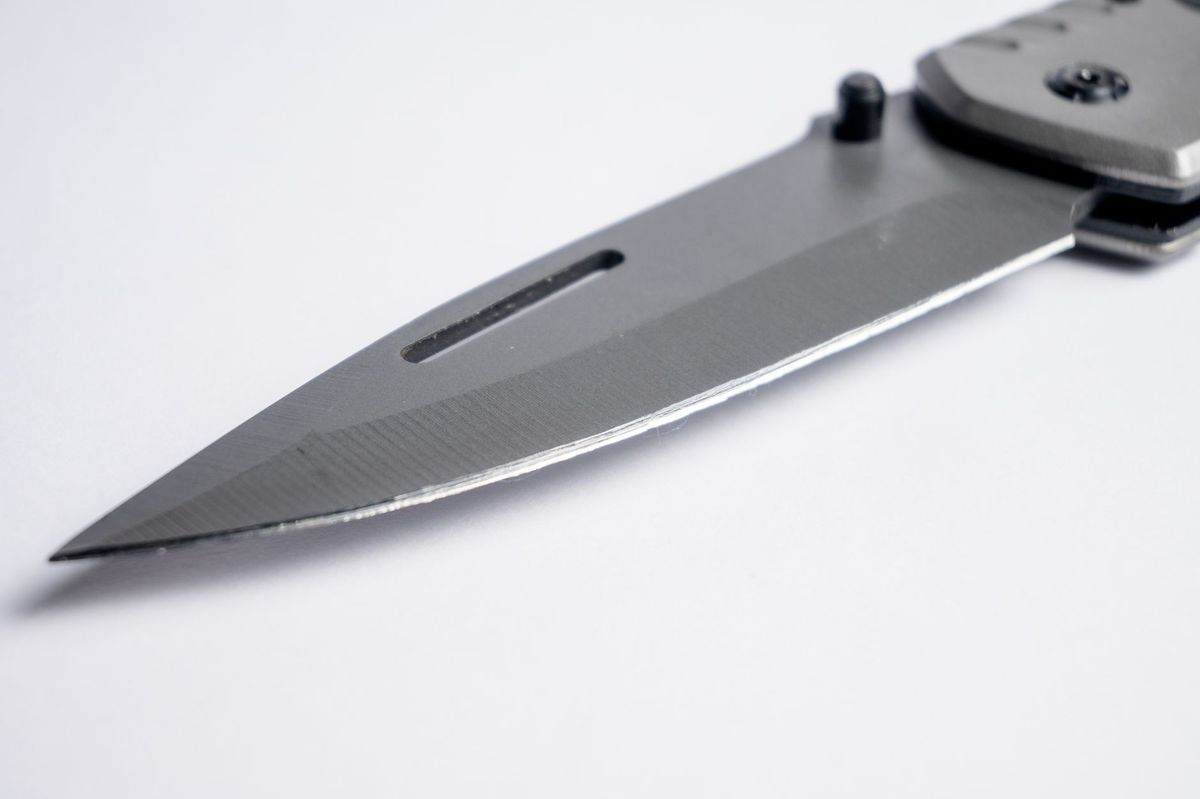 Macro close-up of a pocket knife blade tip showing grind lines