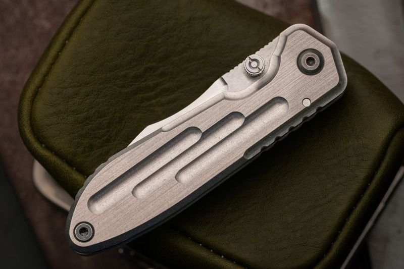 Closed titanium EDC folding knife on leather case, built to last