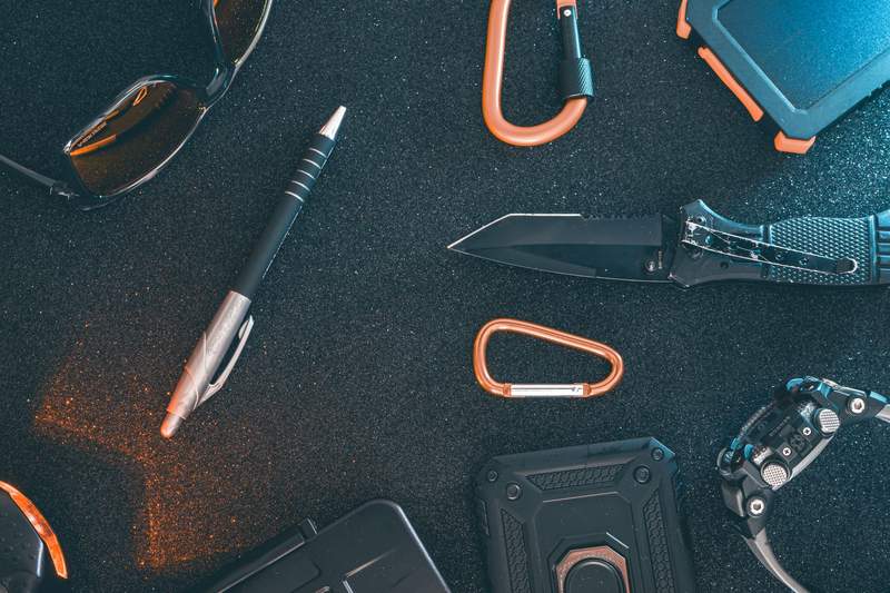 Pocket multitool and everyday carry gear flat lay including knife, pen, and clips