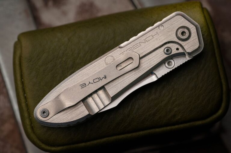 Macro detail of a titanium-handled value pocket knife on leather