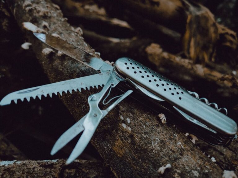 A weathered multitool with saw and scissors open, showing long-term carry wear