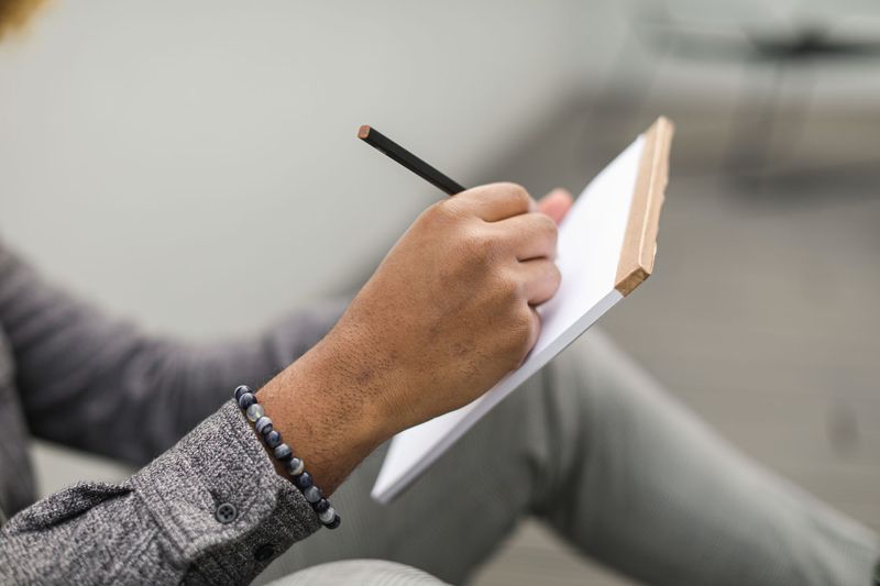 Man writing in a Field Notes style memo book outdoors