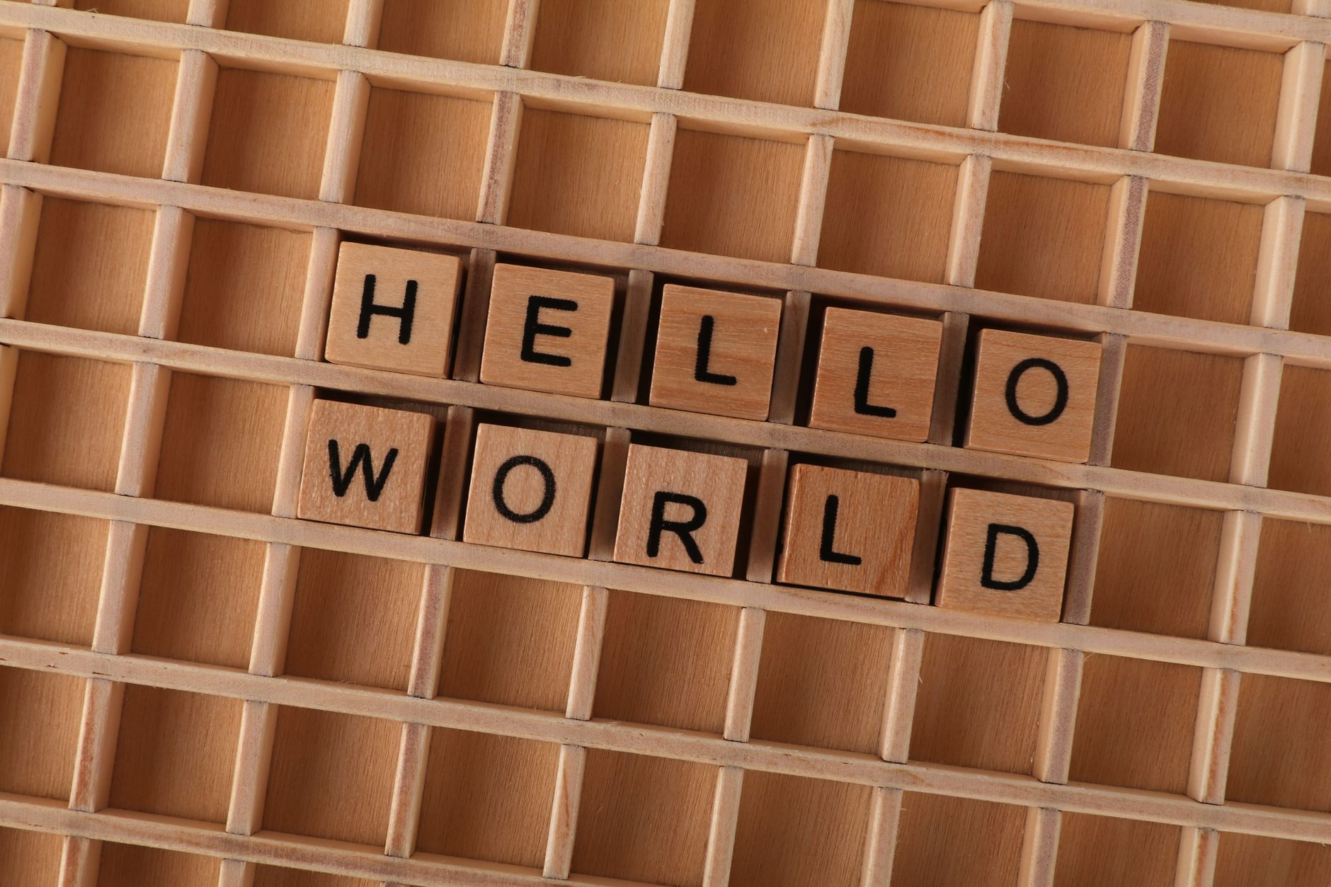 Wooden blocks with letters spelling HELLO WORLD on a wooden grid background, ideal for language conc