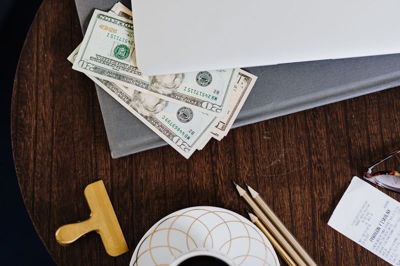 Cash, receipt, and a notebook on a wood desk, illustrating the cost-per-year comparison between Field Notes and Moleskine