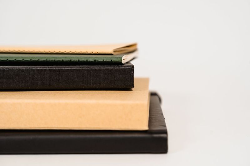 Stack of notebooks with leather, cloth, and kraft paper covers compared side by side