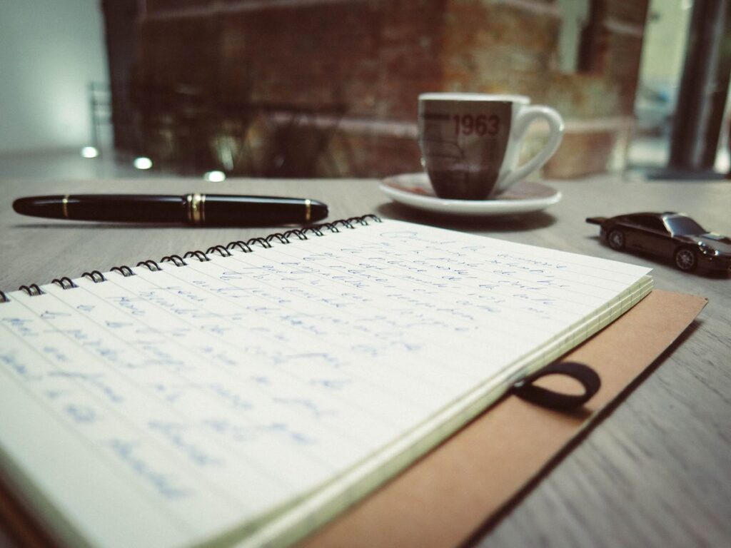Pocket notebook with fountain pen and coffee on a desk, representing a field notes vs moleskine comparison