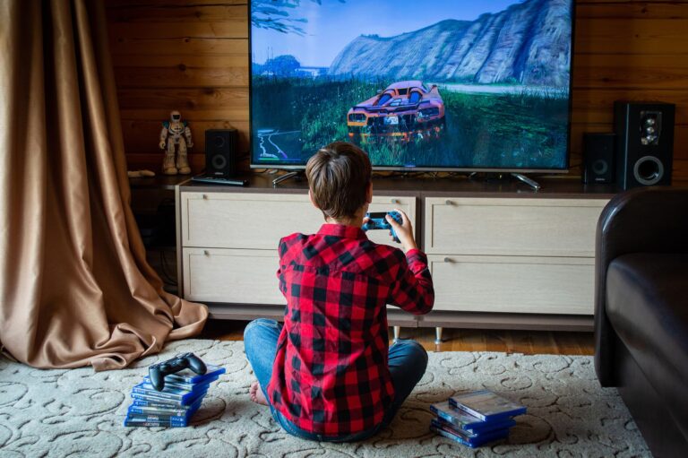 Boy in plaid shirt playing video games on console in a cozy living room setting.