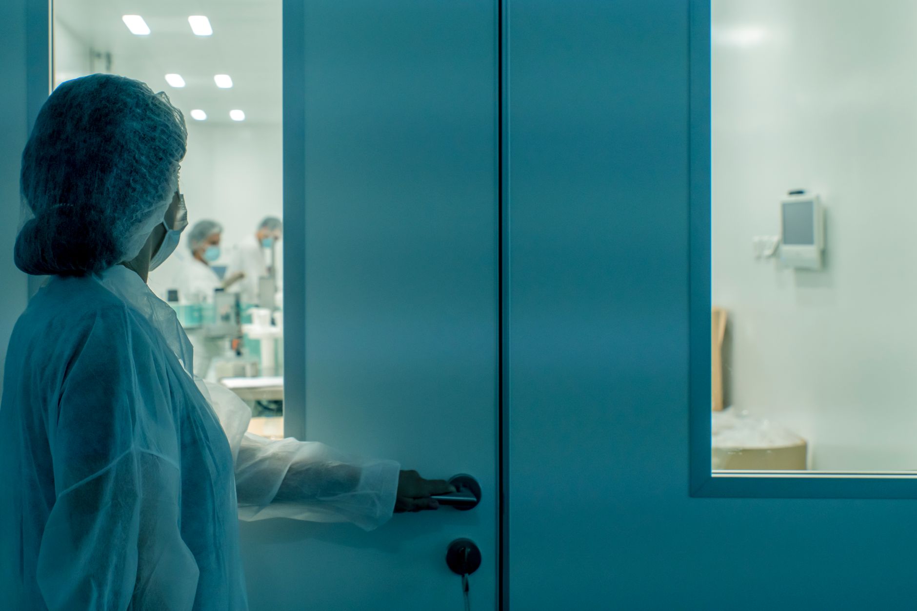 A scientist in protective gear enters a sterile laboratory environment, ensuring cleanliness.