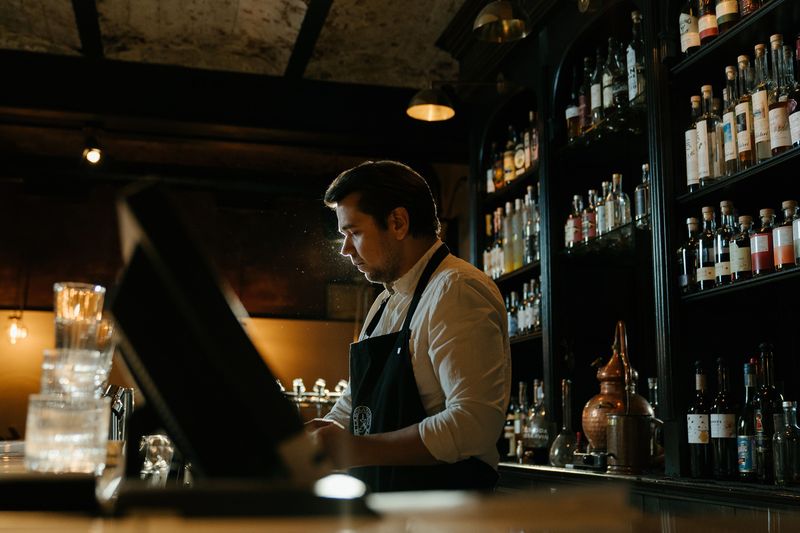bartender working behind the bar shelves during a night shift