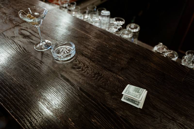 cash tips on a bar counter next to empty glasses, bartender EDC cash handling