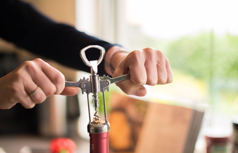 bartender using a personal wine key to open a bottle of wine