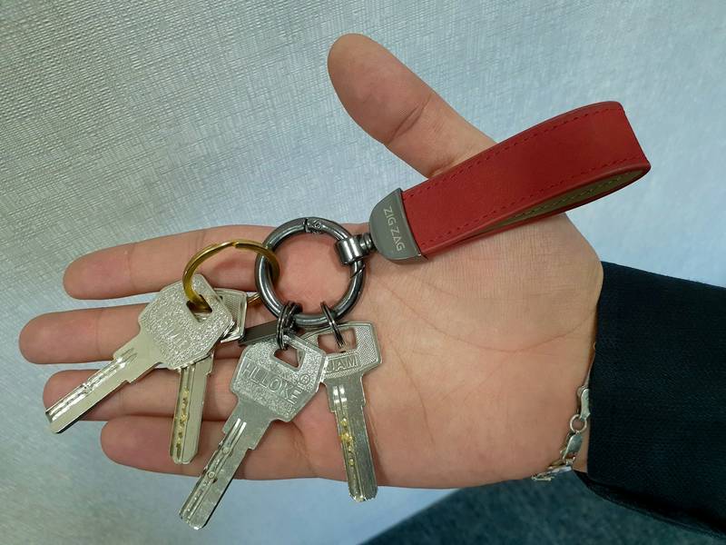 Hand holding keys attached to a leather EDC key organizer fob