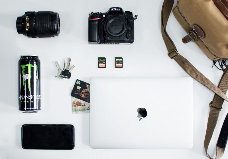Flat lay of camera, laptop, keys, and gadgets showing an overloaded EDC pocket dump