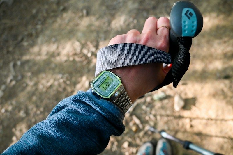 Digital watch worn on wrist during outdoor activity, backlit display visible