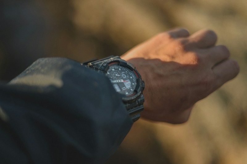 Person wearing a digital EDC watch outdoors in warm evening light