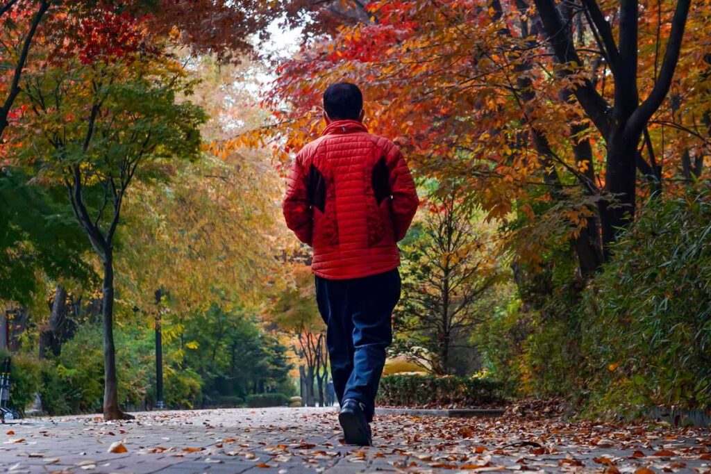 Fall EDC essentials — man walking an autumn path in a light jacket, carrying daily gear
