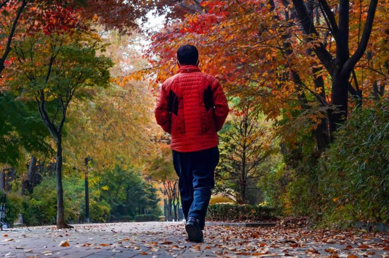 Fall EDC essentials — man walking an autumn path in a light jacket, carrying daily gear