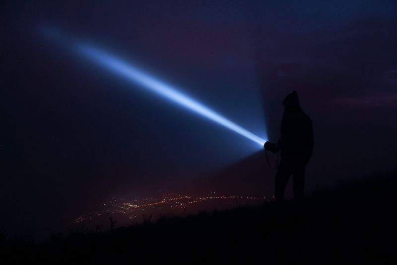 hand holding an edc flashlight at night after daylight saving time ends