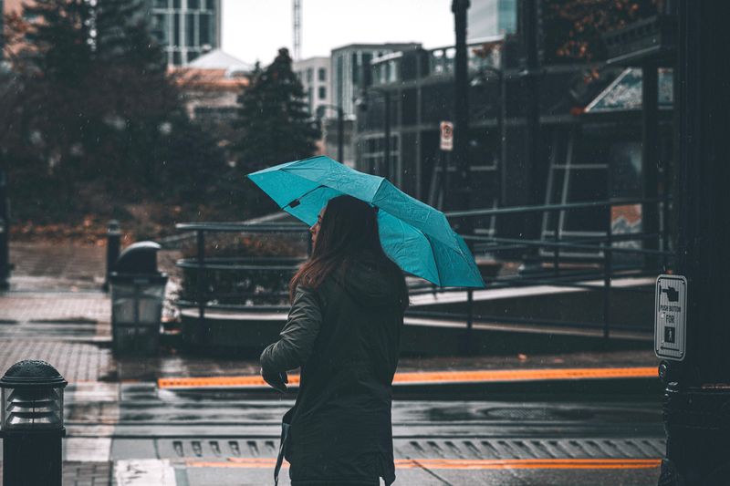 person holding an umbrella in fall rain, wet weather edc gear protection