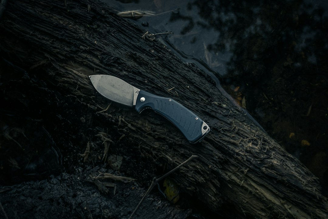 Revo brand Pocket Knife laying on a log