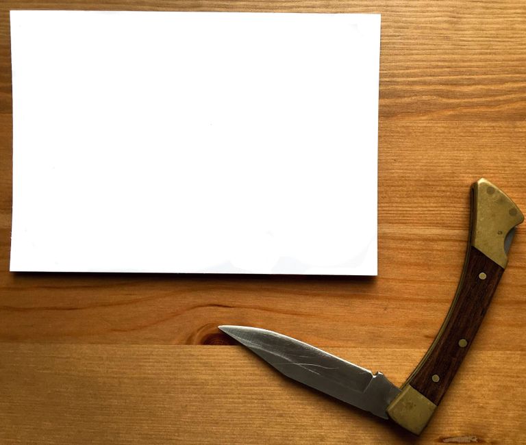 folding pocket knife on wood desk with notebook, EDC flat lay