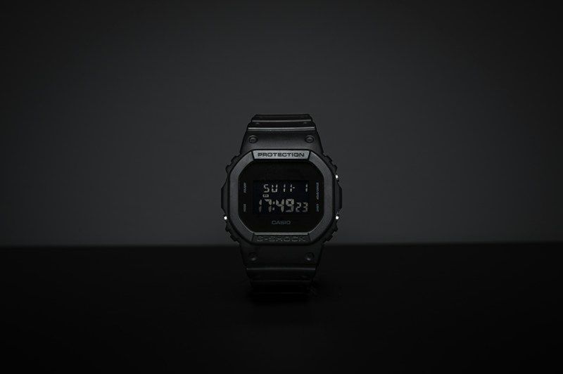 Square-cased G-Shock DW5600 style digital watch in dark studio lighting
