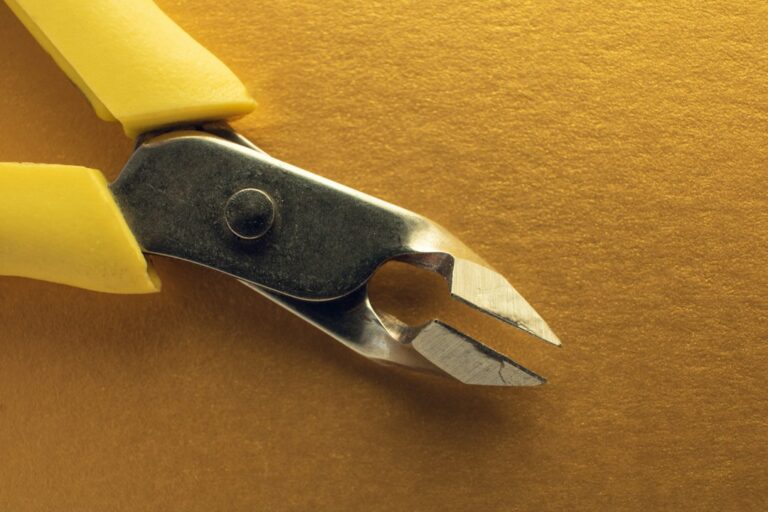 Top shot of the tip of cuticle pliers on golden background