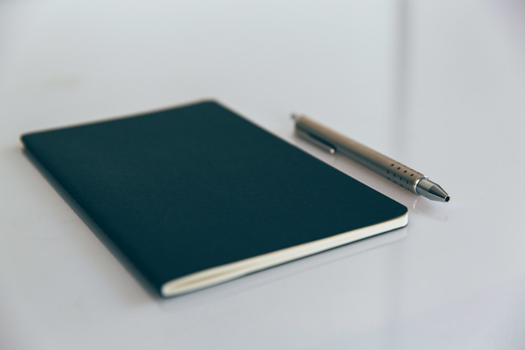 Black blank Moleskine notebook with silver minimal pencil on white desk
