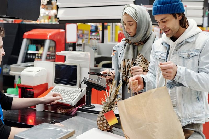 Retail worker scanning items at a grocery checkout counter during a shift