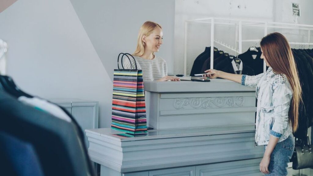 Retail EDC — cashier helping a customer at checkout on a slow sales-floor shift