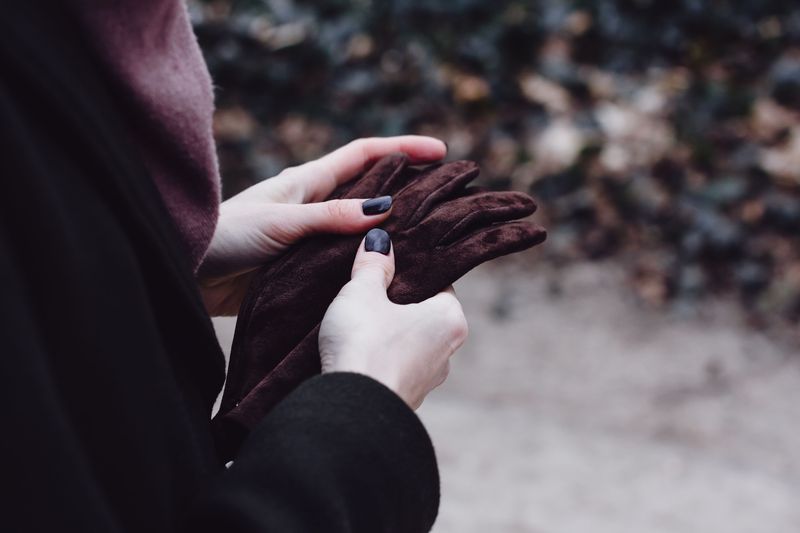 hands putting on leather gloves outdoors in cold weather